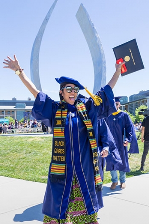 A recent grad holding up their diploma with excitement