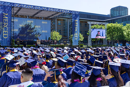 A sea of blue graduation caps with blue and yellow tassels