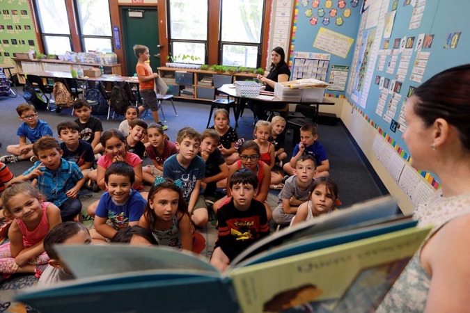 Teacher reads book to a group of kids