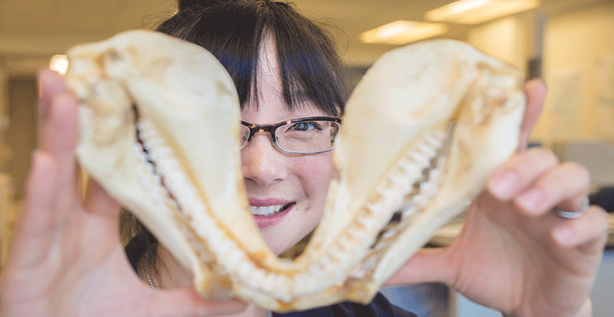 Focused view of Professor Sora Kim's face behind a shark jaw bone