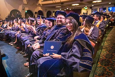Graduate students pose after receiving their diploma.