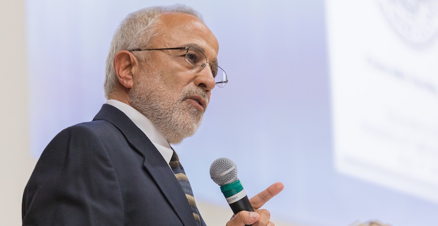 Professor Abbas Ghassemi onstage holding a microphone