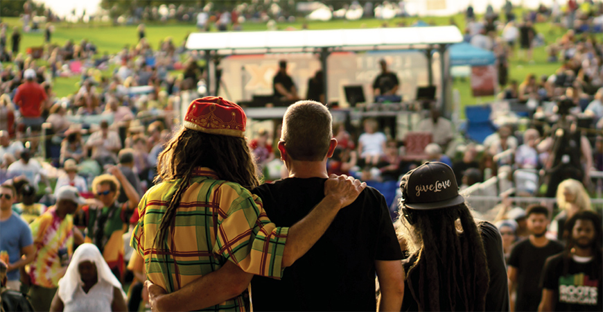 Stage view of three performers looking out to a concert crowd