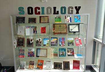 Display case of published books and awards from UC Merced Sociology professors