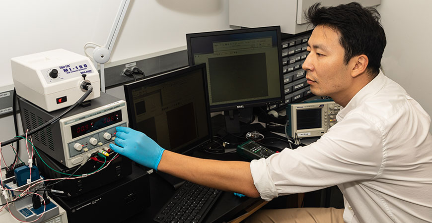 Professor Min Hwan Lee turning knob on electrochemical energy equipment