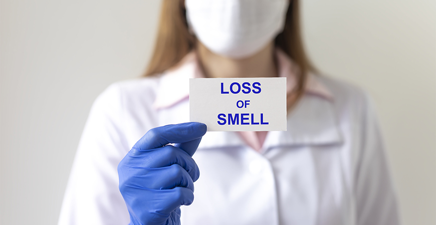 Scientist holds paper that reads "Loss of smell"