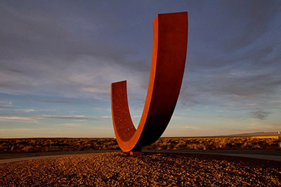 A clay red U-shaped sculpture in the New Mexico desert