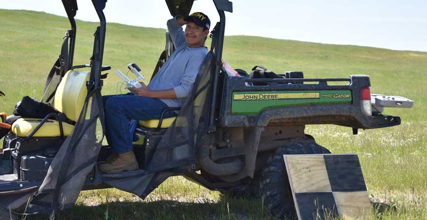 Mechanical engineering major Arturo Ramirez Reyes holds a drone while sitting in a tractor. 