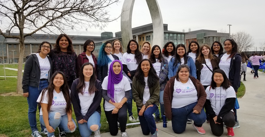 Student members of the Society of Women Engineers pose in front of Beginnings sculpture