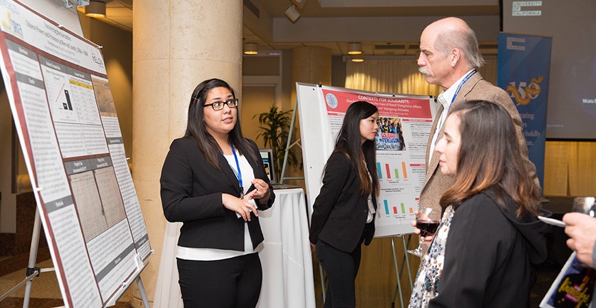 UC Merced's Verenize Arceo presents her research as two onlookers listen.