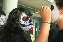 student painting another's student face for chicano history month